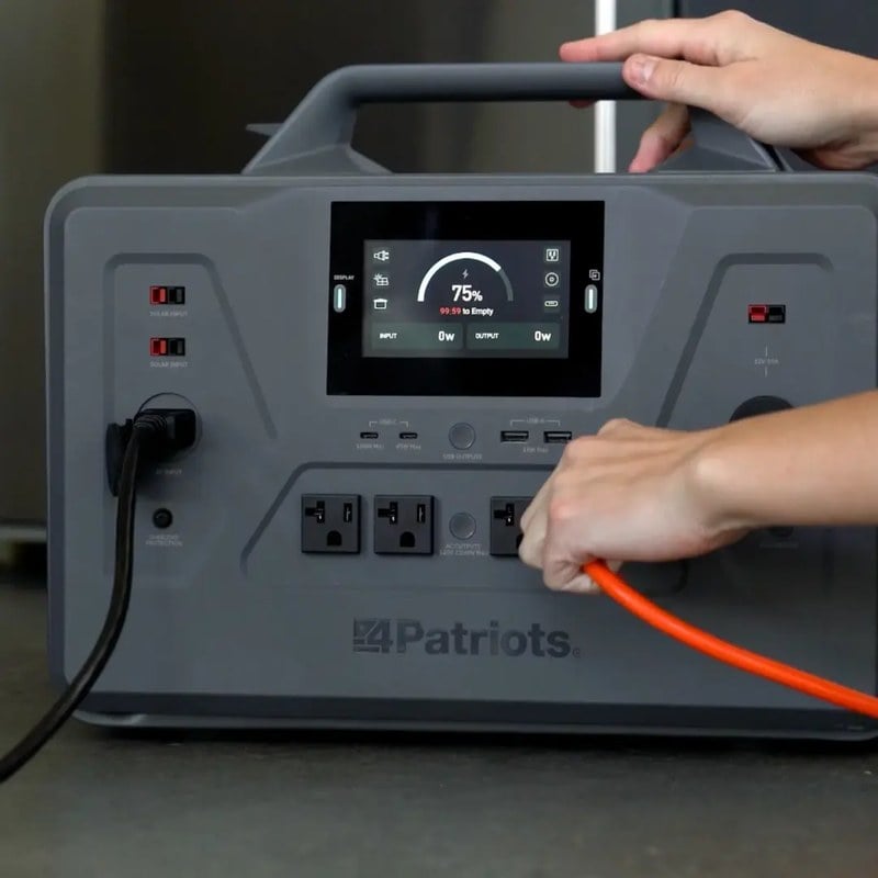 Hands plugging an extension cord into the front outlet panel of a 4Patriots Patriot Power Generator 2200X showing 75 percent charge