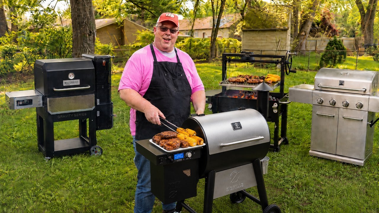 James Hills at the grill surrounded by a backyard cooking stack including a Masterbuilt Gravity Series smoker, a Z Grills pellet grill, a Santa Maria-style grill, and a stainless 4-burner gas grill