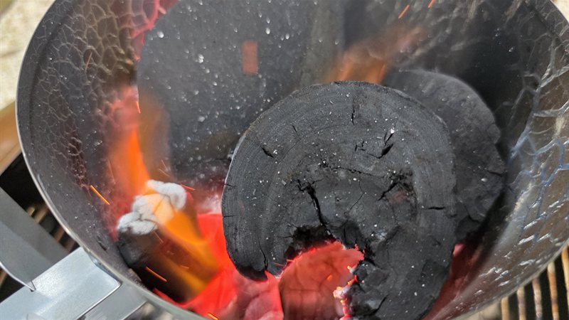 A large piece of Bear Mountain lump charcoal catching flame inside a chimney starter
