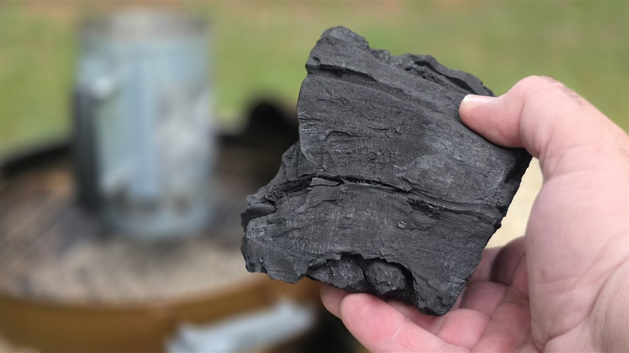 A large chunk of Bear Mountain hardwood lump charcoal held in hand with visible wood grain