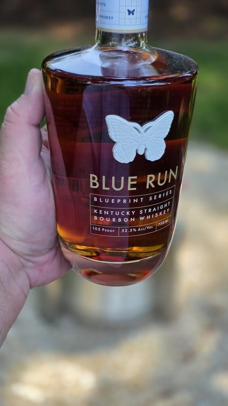 Blue Run Blueprint Series bourbon bottle held in hand, showing the viceroy butterfly and French-cut glass