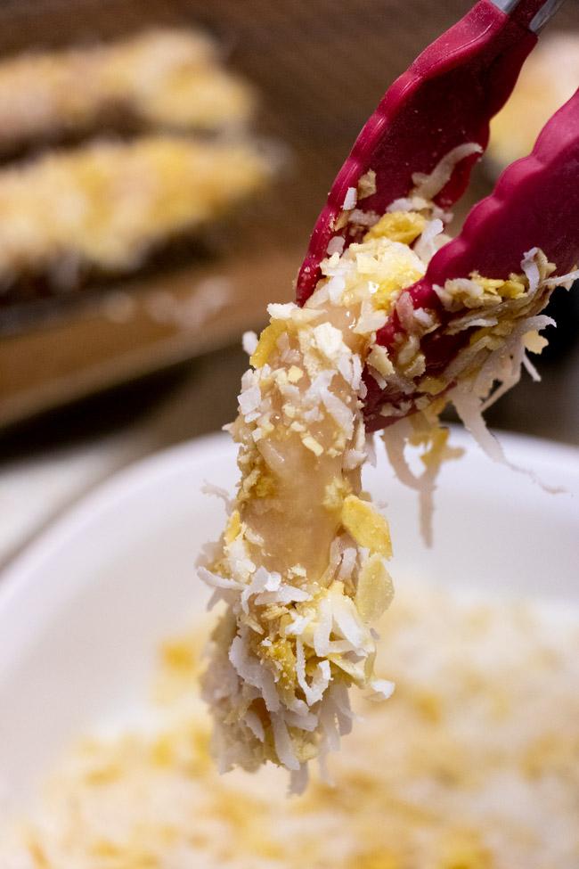 dredging the chicken tenders in coconut and cracker crumbs before baking