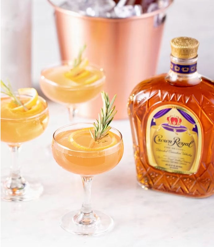 Crown Royal Rose champagne cocktail with rosemary garnish and Crown Royal Fine De Luxe bottle
