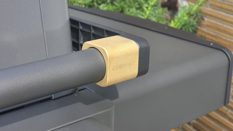 Brass collar where the lid handle meets the lid on the Current Model G2 electric grill, stamped with the Current brand mark
