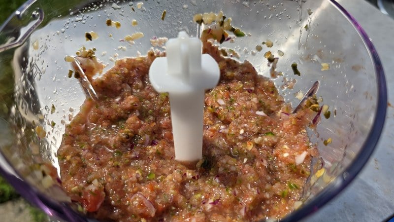 The same FRESKO chopper bowl after blending, holding coarse fresh salsa with visible pieces of tomato, chile and onion