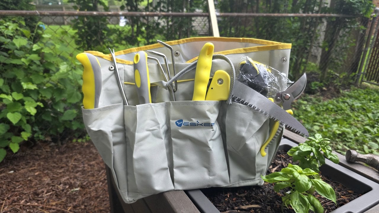 Yesker 10-piece garden tool set loaded in its gray and yellow tool bag on a raised bed next to a basil plant