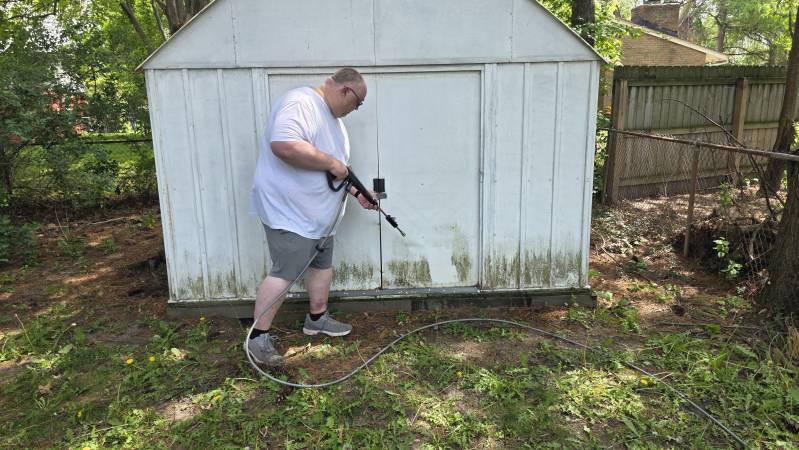 cleaning mold off garden shed with pressure washer