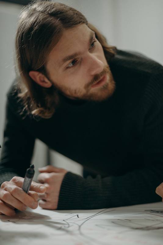 man in black sweater holding marker pen 3205590