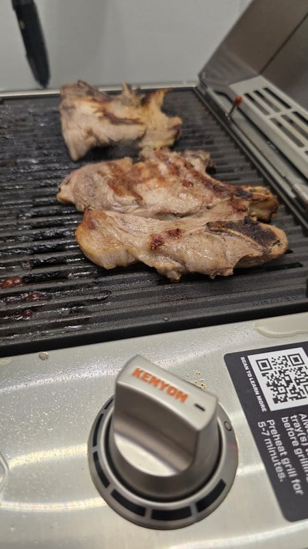 Browned pork chops on the Kenyon City Grill next to the KENYON control knob and preheat label