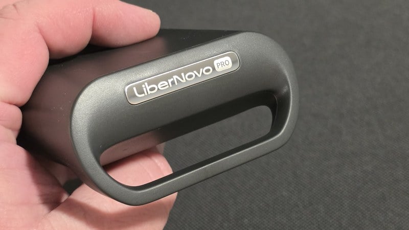 A LiberNovo Maxis armrest pad held in one hand, showing the LiberNovo PRO badge on the end cap
