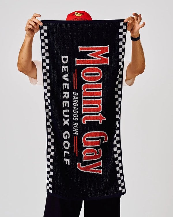 Black and white Mount Gay x Devereux Golf towel with red lettering and checkered borders