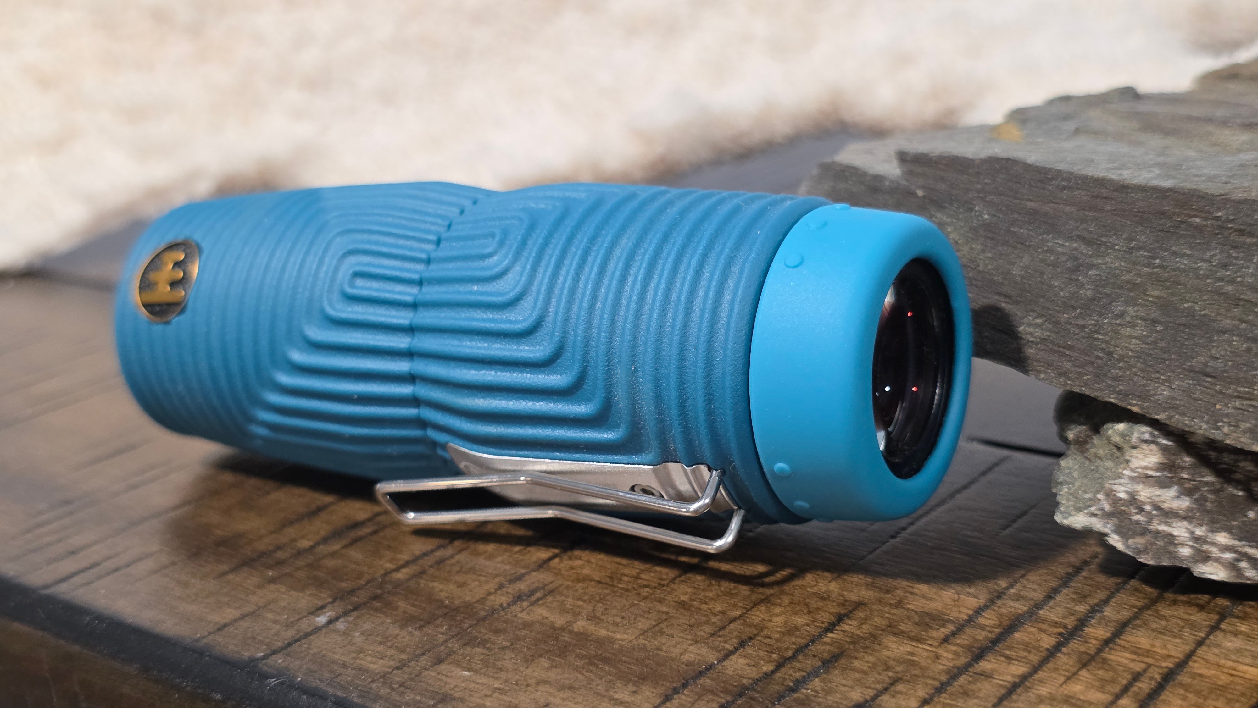 Nocs Provisions Zero Tube 8x25 monocular in blue Wave Armor lying on its side next to slate rocks