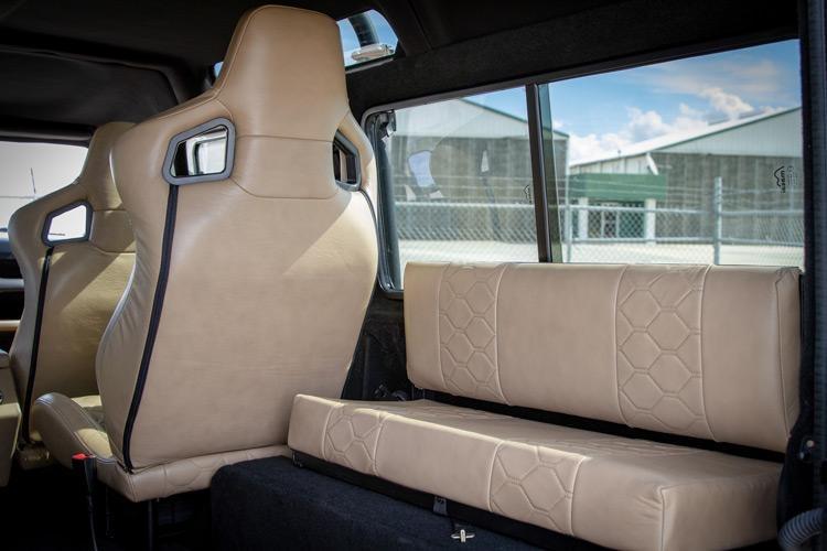 custom leather interior with bucket seats and rear bench in loading area on project viking land rover defender