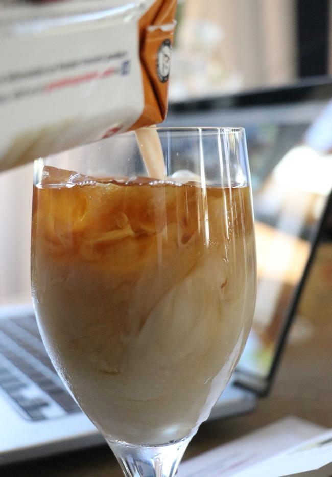 pouring carmel premier protein into iced coffee