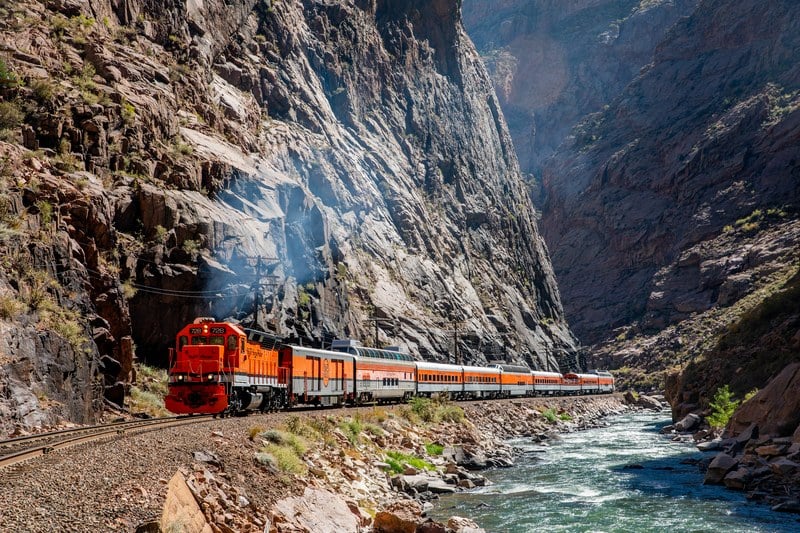 The Royal Gorge Route Railroad running along the base of a sheer canyon wall beside the Arkansas River