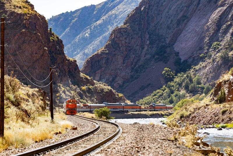 Wide view of the Royal Gorge with the Royal Gorge Route Railroad train small against the canyon and track curving in the foreground