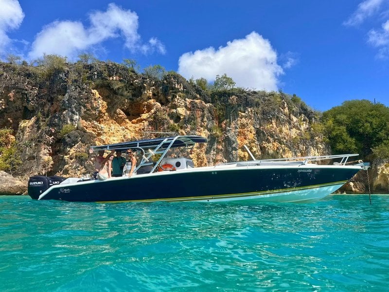 A 35-foot Malargo private charter boat from EXPLR.SX anchored below limestone cliffs in clear turquoise water