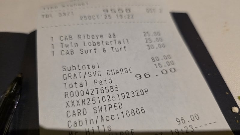 Cruise steakhouse receipt photographed on a phone - surf and turf, gratuity, and the cabin charge