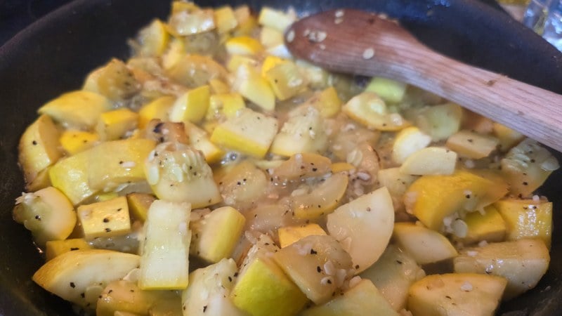 Chopped yellow summer squash sauteing in butter and olive oil with minced garlic and cracked black pepper