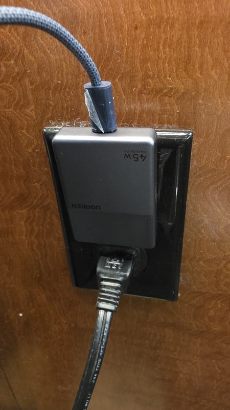 The UGREEN Nexode Air Slim 45W charger plugged into a wall outlet with a braided USB-C cable running from it