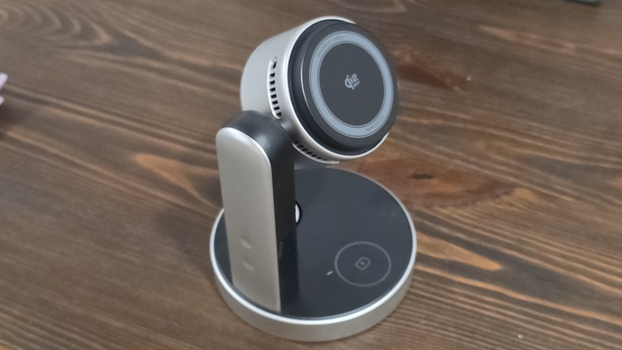 The UGREEN MagFlow Pro 3-in-1 wireless charging stand on a wood desk, its round Qi2 25W phone pad and side cooling vents facing the camera