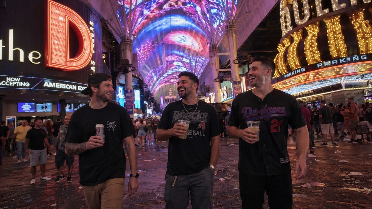 Three guys laughing on Fremont Street under the canopy holding drinks during a Vegas guys trip