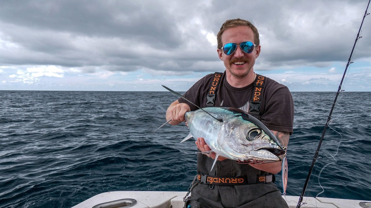 Josh Phillips of Washington's Evergreen Coast holding an albacore tuna on the deck of a fishing boat offshore