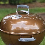 The copper Weber Original Kettle Premium 22-inch charcoal grill with the lid closed in a backyard