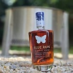 Blue Run Blueprint Series Kentucky Straight Bourbon Whiskey bottle standing on gravel in front of a fire pit