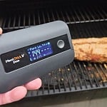 MeatStick V Duo Smart Base displaying 144°F next to a smoked pork loin on the grill