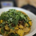 Cooked yellow summer squash and caramelized garlic in a white bowl under a heap of freshly picked basil