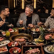 Three friends sharing hot pot, Korean BBQ and sushi during a Las Vegas guys trip in an upscale Asian restaurant