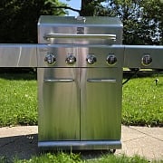 Kenmore 4-Burner Gas Grill with Side Searing Burner in stainless steel, lid closed, on a backyard patio