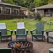 Fire pit ringed with green Adirondack chairs at Hemlock, the adult summer camp resort in the Catskills