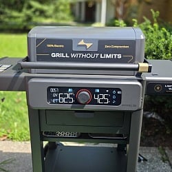 The Current Model G2 electric grill on its cart outdoors, display lit with both zones set to different temperatures