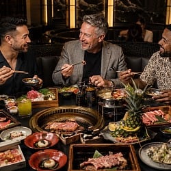 Three friends sharing hot pot, Korean BBQ and sushi during a Las Vegas guys trip in an upscale Asian restaurant