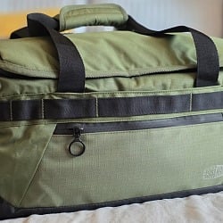 BagSmart Paz 43L Duffle Backpack in olive green resting on a bed