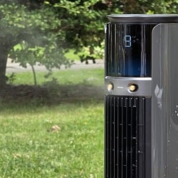 Dreo TurboCool 711AS outdoor misting fan running on a lawn with mist blowing across the yard