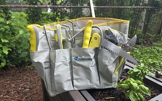 Yesker 10-piece garden tool set loaded in its gray and yellow tool bag on a raised bed next to a basil plant