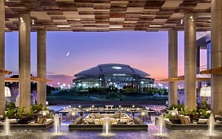 Clover Club lawn at Live! by Loews Arlington facing AT&T Stadium at dusk (photo credit: Loews Hotels)