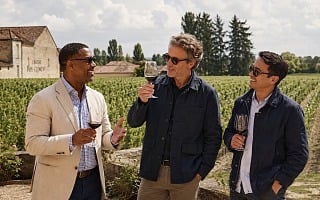 Three men tasting red wine among the vines at Chateau Pape Clement outside Bordeaux, France on a guys trip