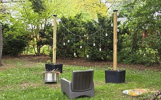 Step2 Firefly String Light Pole Stand with Planter installed in a backyard hangout zone with Solo Stove firepit and Step2 Switchback patio chair