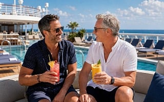 Two men with non-alcoholic drinks relaxing by the pool on a cruise ship deck
