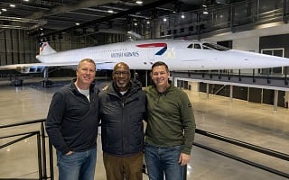 Three men standing in front of Concorde Alpha Foxtrot in the hangar at Aerospace Bristol