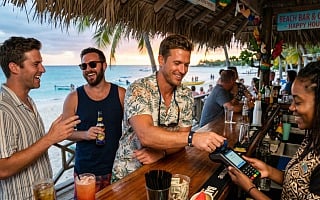 Man on a Caribbean cruise paying with an RFID wristband at a beach bar