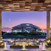 Clover Club lawn at Live! by Loews Arlington facing AT&T Stadium at dusk (photo credit: Loews Hotels)