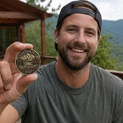 man holding a custom Catskills bachelor party challenge coin at a mountain cabin