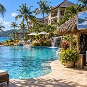 All-inclusive resort pool beside a fishing excursion and dive shop shack with scuba tanks and fins