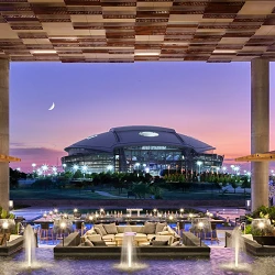 Clover Club lawn at Live! by Loews Arlington facing AT&T Stadium at dusk (photo credit: Loews Hotels)