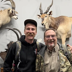 Colton Cozza and his father together in a South African hunting lodge trophy room after their Eastern Cape plains game hunt